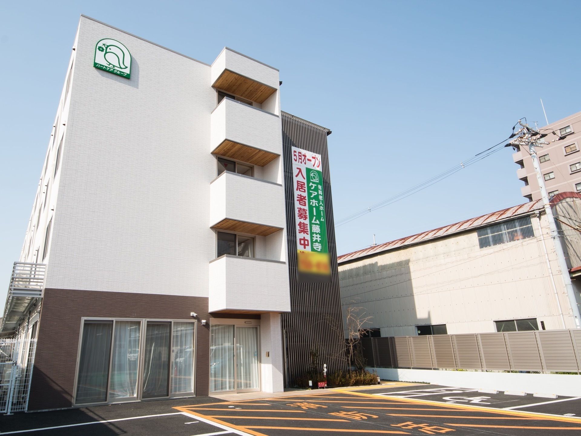 4階建ての大きな建物で、一見施設には見えないすらっとしたデザイン。側面の外壁にはホームのシンボルマークが描かれている。