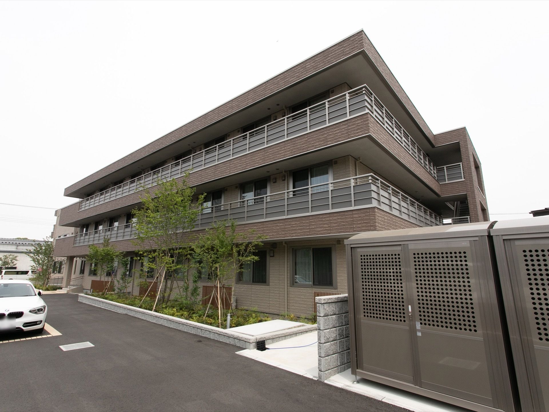 青空の下に建っている鉄骨造の建物の様子。サービス付き住宅アミカの郷船橋の外観