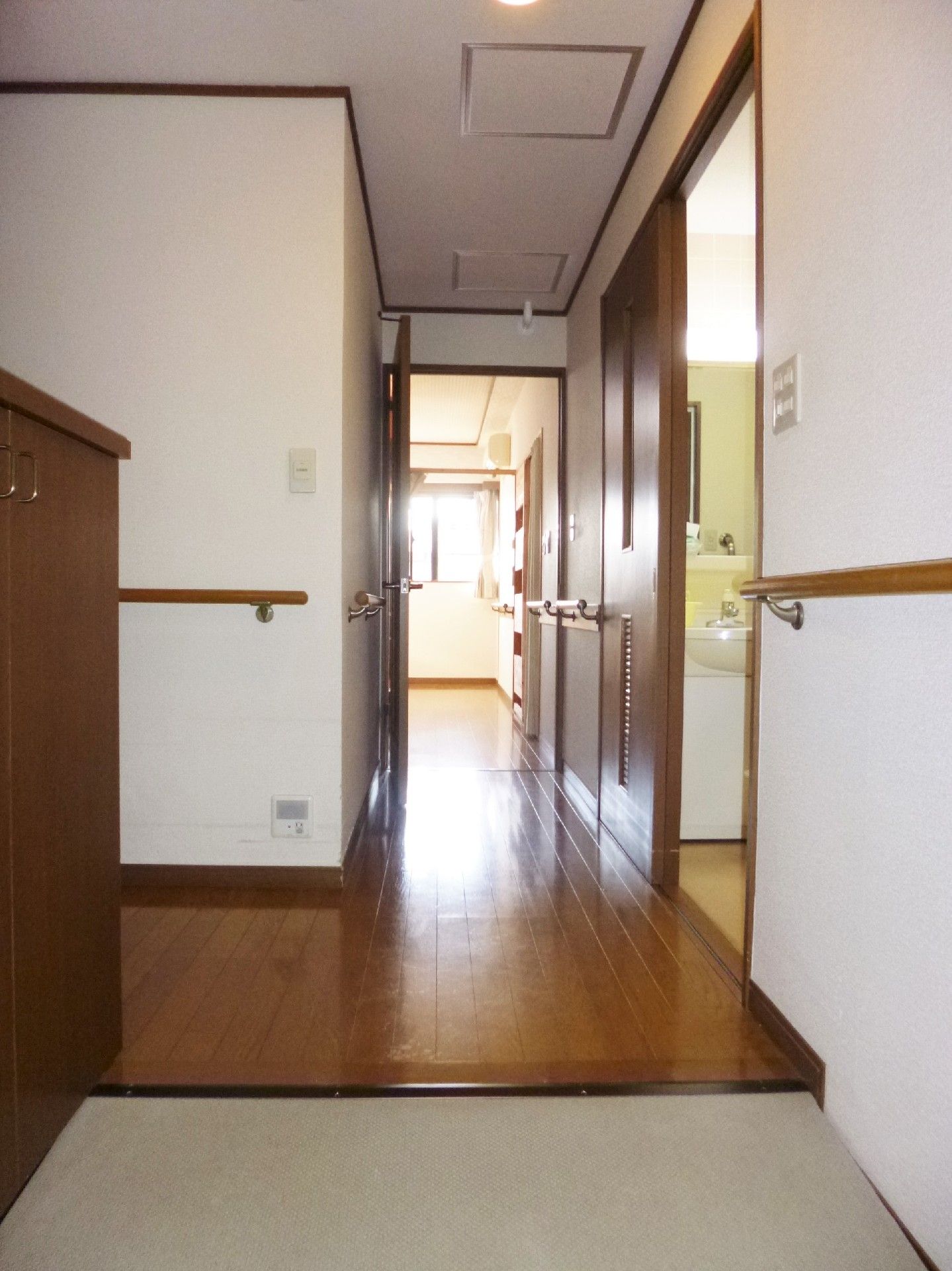 壁には手すりが設置され、まっすぐな廊下の奥とには日当たりのいい部屋が見える。玄関を入ってすぐ右側にも部屋がある。