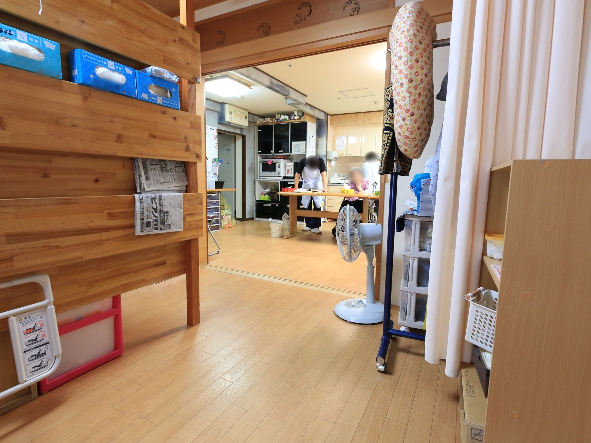 木のぬくもりが感じられる館内で、奥にキッチンが備え付けられている共有スペースが見える。床は木目調のフローリングとなっている。