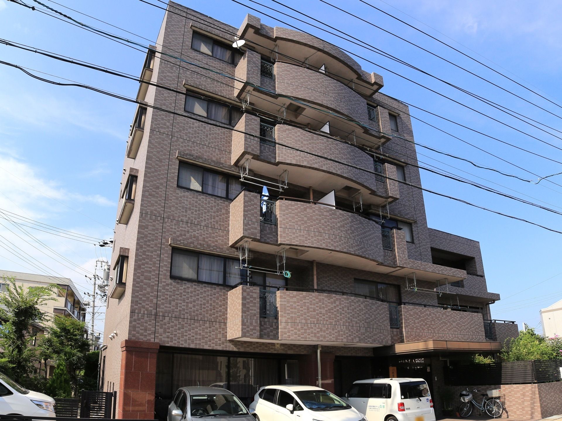 住宅街の中にある施設で、外壁はブラウンで落ち着いた色合いとなっている。２階以上の部分にはベランダスペースがとられている