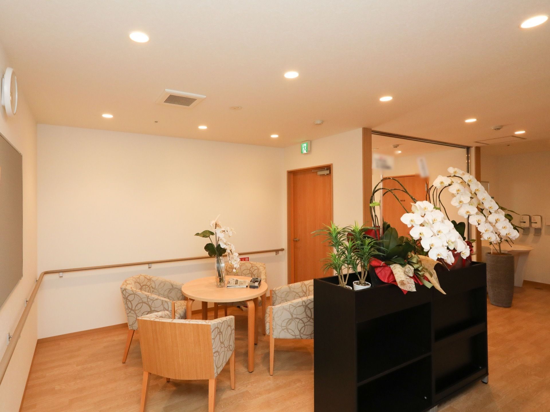施設の一角に談話コーナーが設けられている。テーブルや棚には花が飾られており華やかである。廊下に手すりが完備されている。