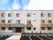 ３階建ての建物はベージュの外壁にブラウンのストライプが縦に何本も入っている。