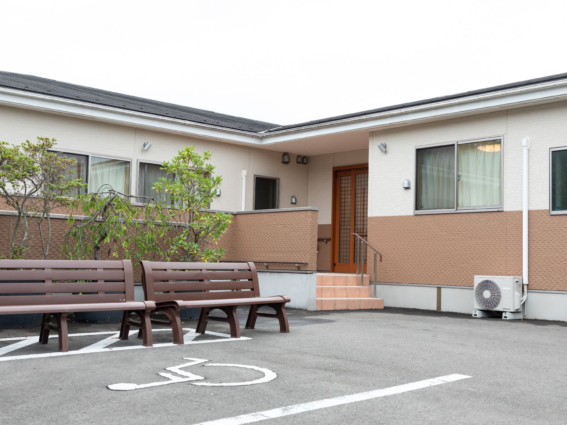 ベンチと植木鉢が置かれた駐車場に面している白い壁の建物