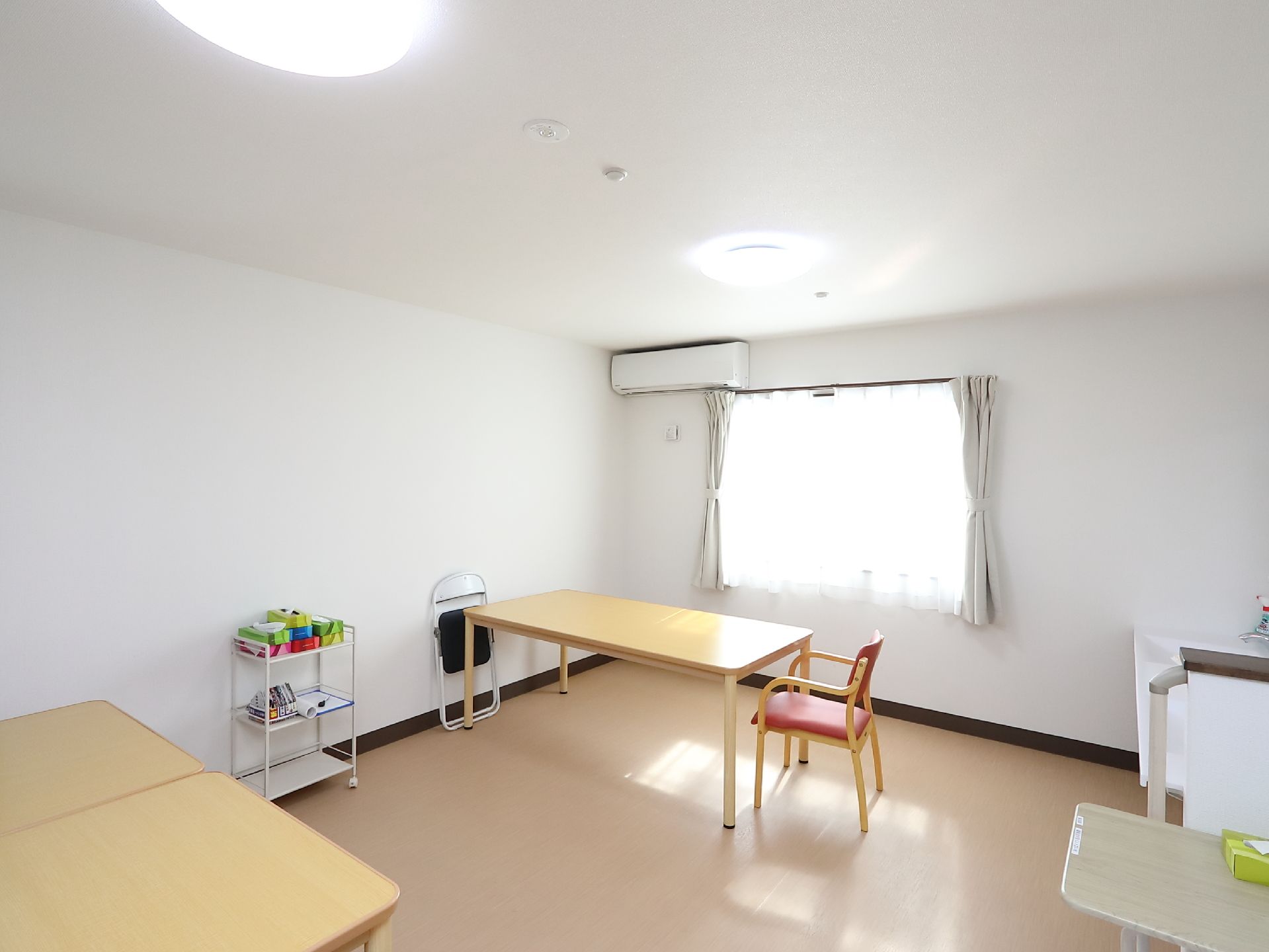 大きな窓があってとても明るい休憩コーナーがある。いろいろなサイズのテーブルがある。ワゴンにはティッシュペーパーの箱がいくつも置かれている。