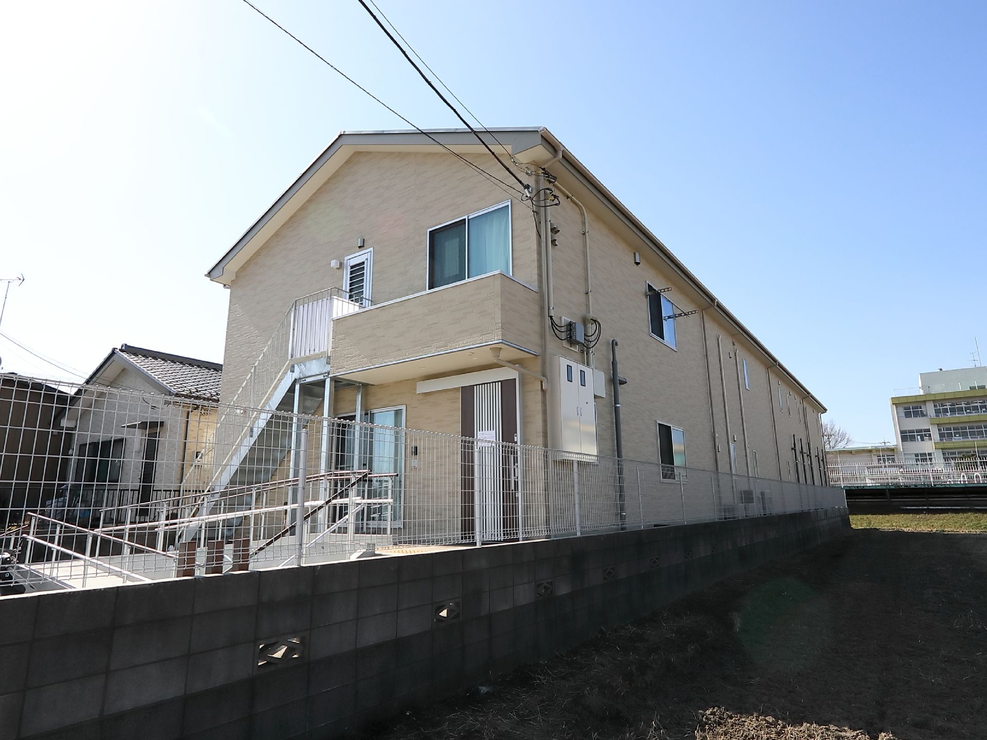 奥行きのある２階建ての施設である。玄関に向かって右隣の敷地は、広い空き地になっている。白いフェンスで囲まれている。