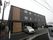 ３階建ての施設は、濃いグレー系の落ち着いたデザインである。手前には駐車場があり、軽自動車が所々に置いてある。