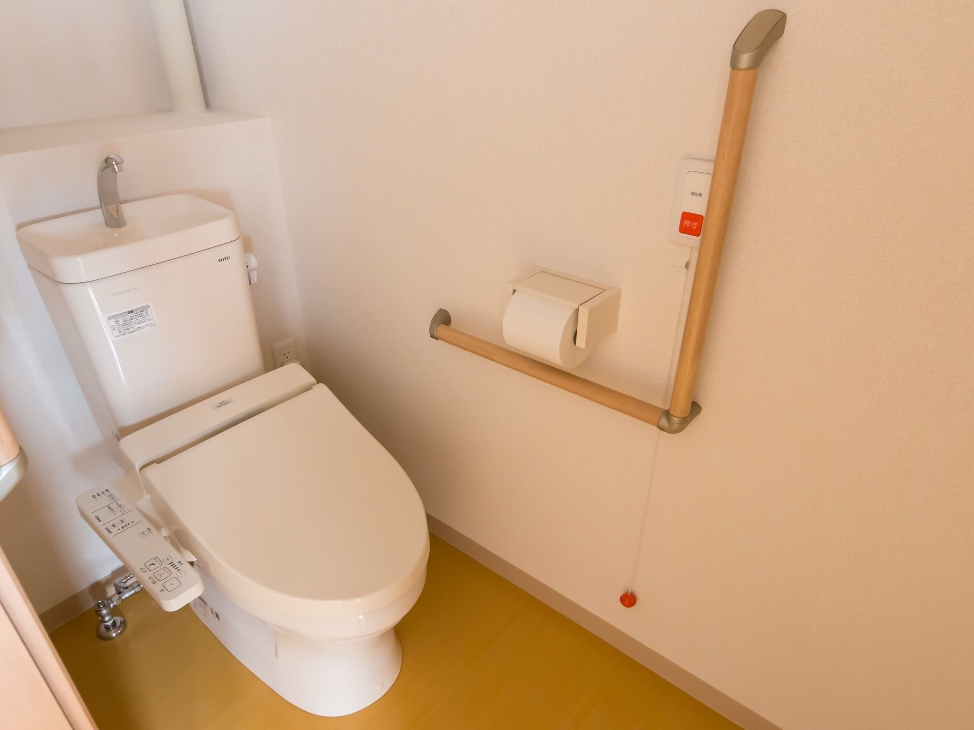 トイレの手すりの近くには赤い呼び出しボタンがある。紐を引っ張ることによりスタッフを呼ぶことができる。