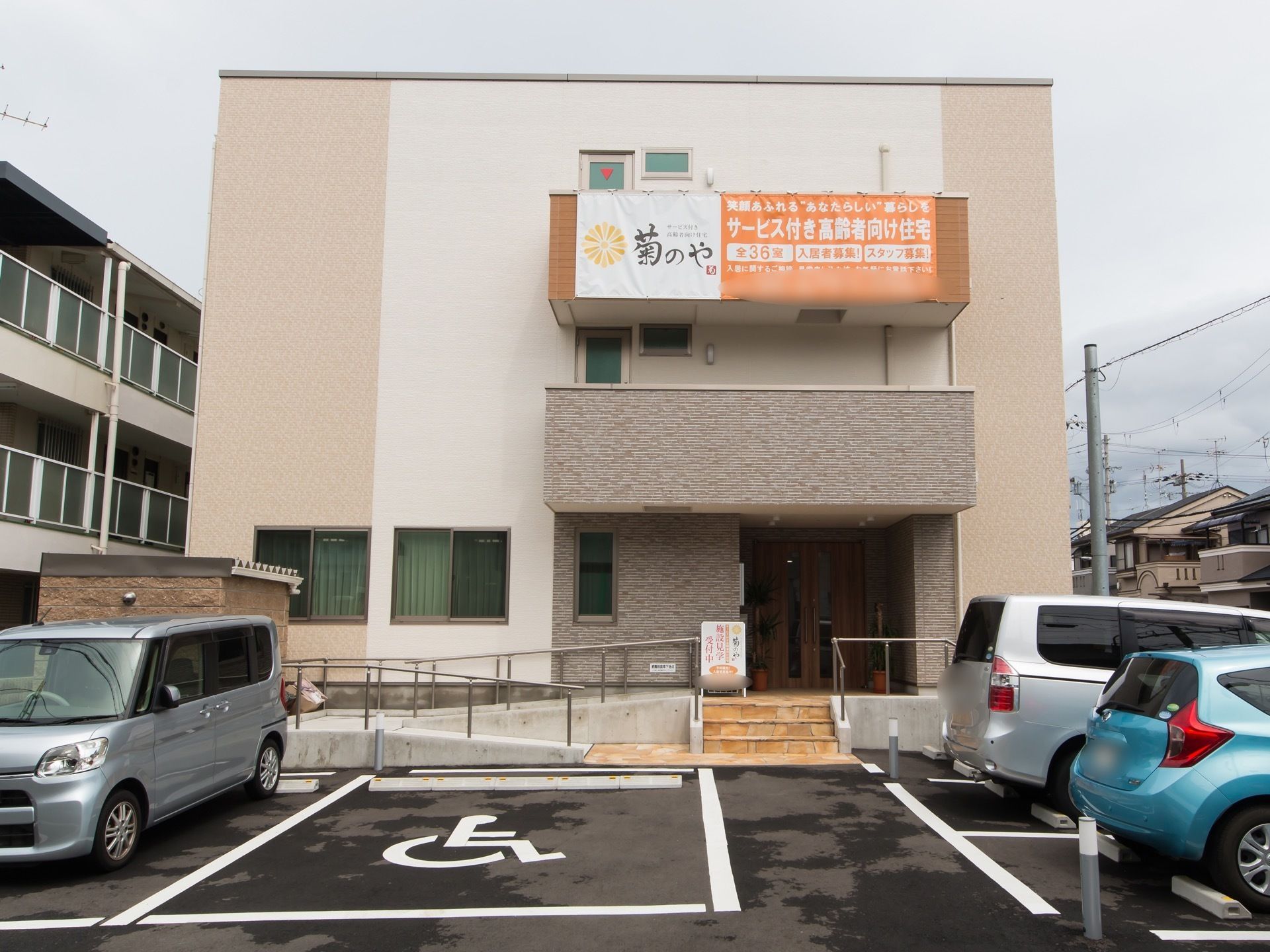 ベージュ色と白色の明るい外観である。高い位置に施設名称の入ったオレンジの垂れ幕が下がっていて、遠くから確認することができる。