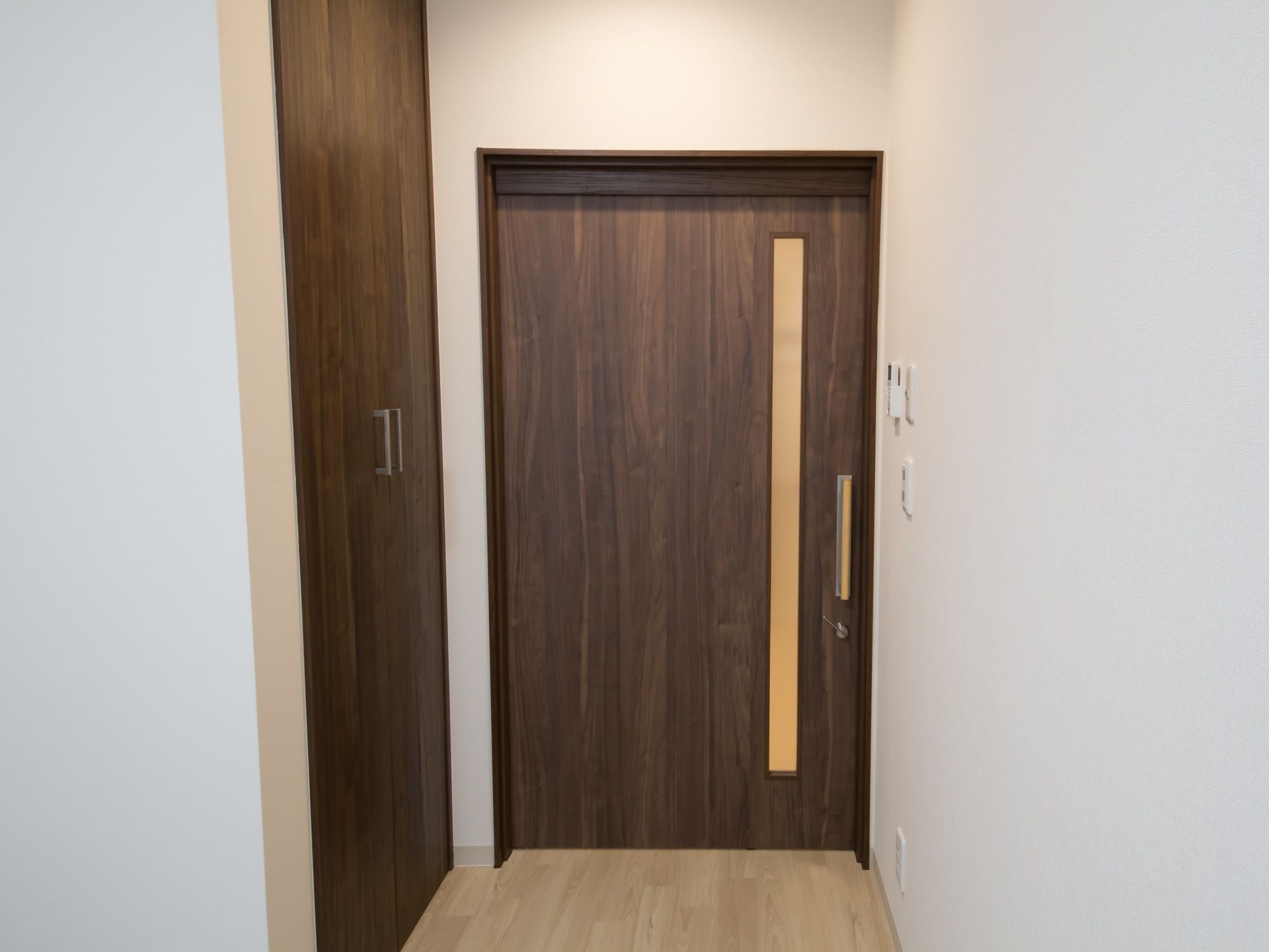 居室の扉は幅が広く、落ち着いたダークブランを採用している。入り口の脇には両開きの収納スペースがある。