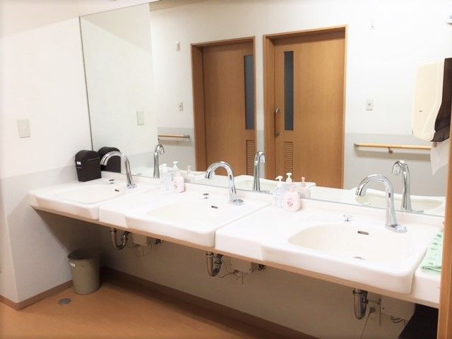 二つ洗面所が並び、壁一面が鏡となっている。足元には車いすのためのスペースも確保されている。