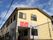 濃いクリーム色を基調とした外観。2階建てで、住宅の周りには木が植えられている。