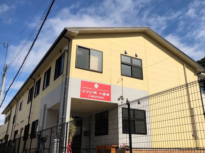 ２階建ての建物には三角の屋根が付き、クリーム色で暖かい雰囲気。敷地内には木が植えられている。
