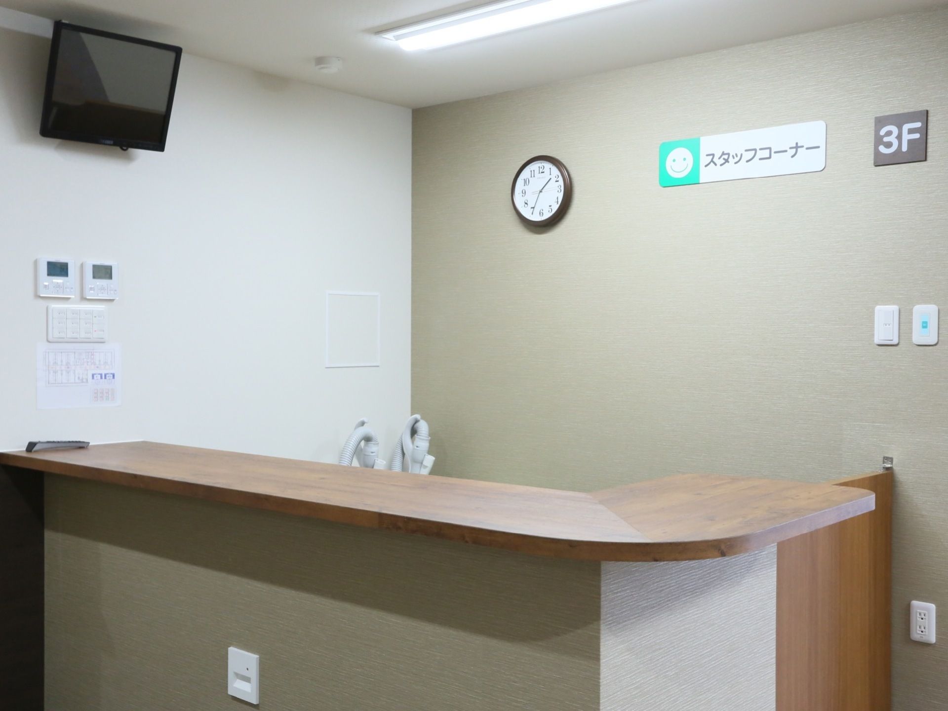 壁にスタッフコーナーと書かれたスペースがあり、その前にはカウンターが設置されている。空調管理の操作盤や照明のスイッチがある。