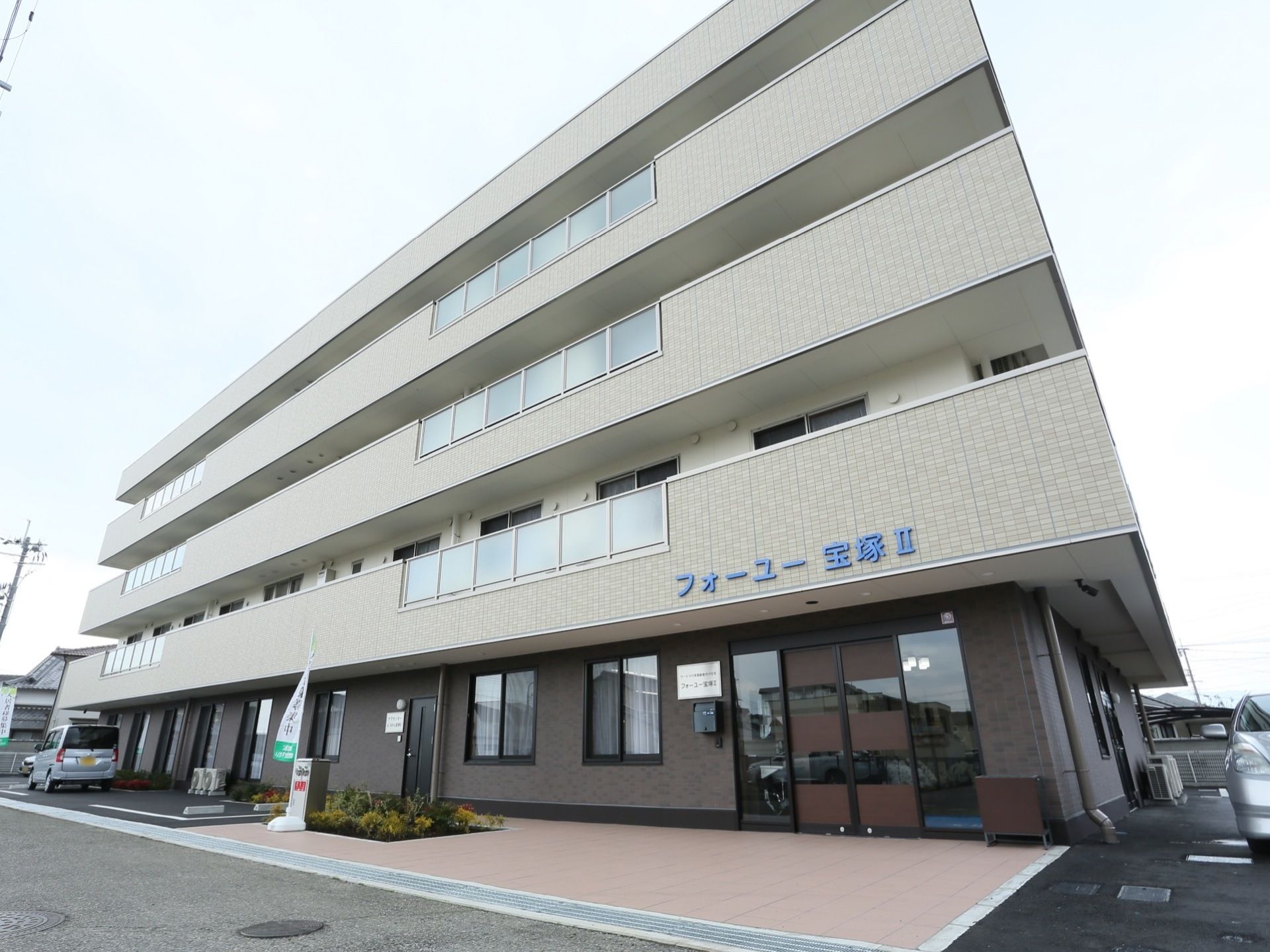 ４階建てで、２～４階までベランダが設置されている。２階のベランダの部分に、青い字で施設名が書かれている。