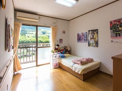 窓の外に自然豊かな景色が見えている部屋の様子。ベッドやタンスなどがあるフリースペース