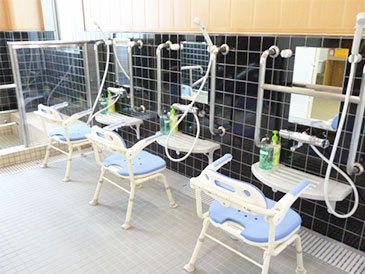 シャワーチェアや手すりが取り付けられている大浴場の写真。高齢者施設の浴室