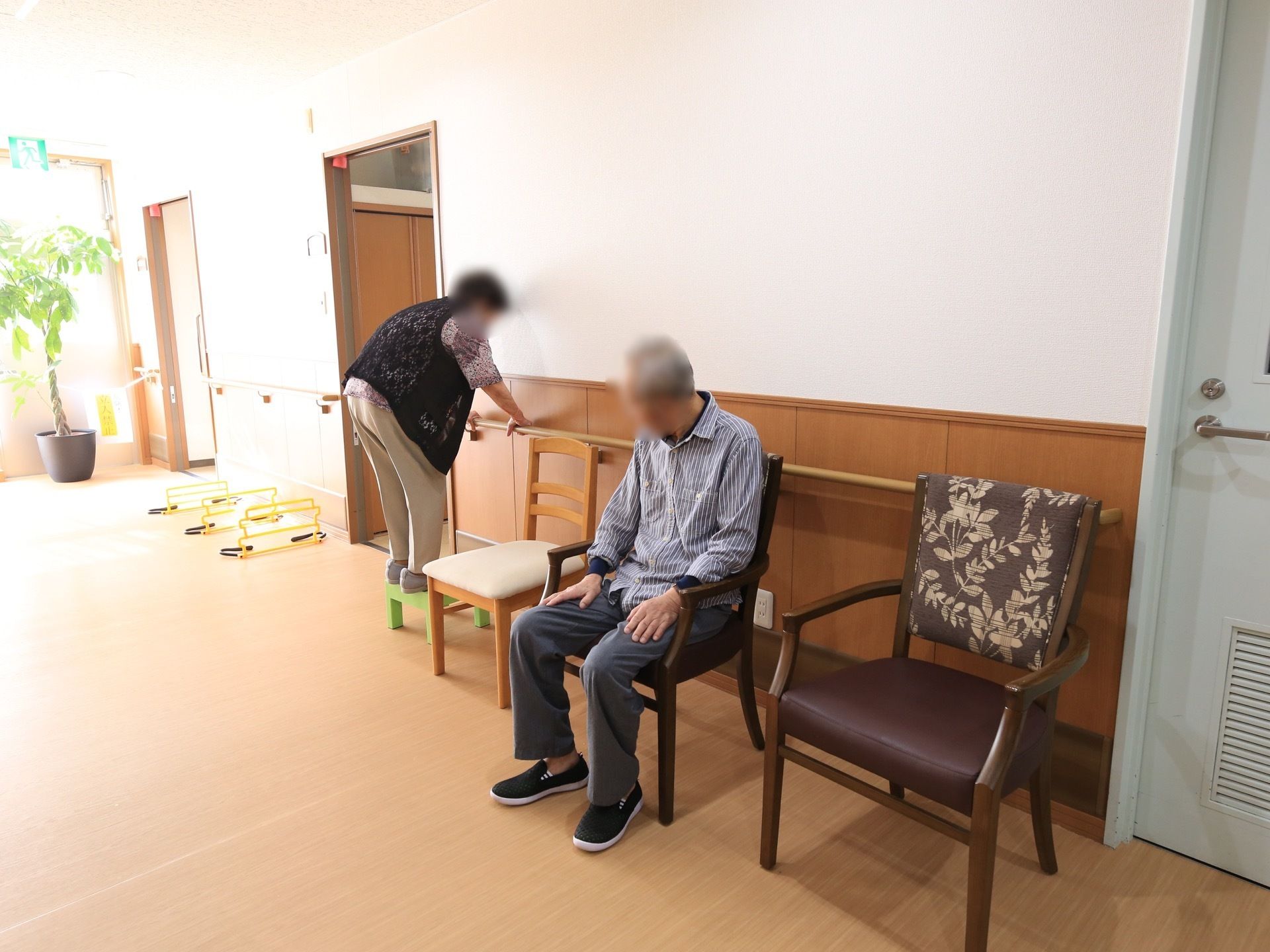 廊下の手すりに掴まりながら、安全に踏み台昇降の訓練が行える。傍らには椅子が置かれ、休憩を取れるようになっている。