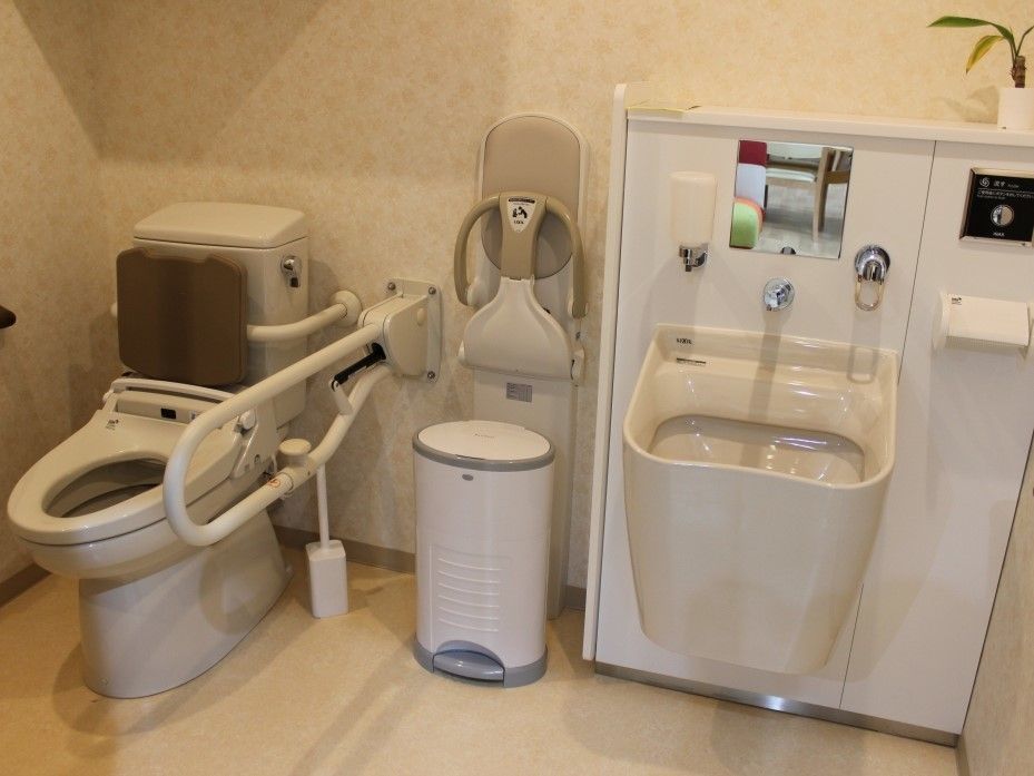 可動式の手すりと介護用の設備があるトイレの様子。車いすのまま入れる広さ