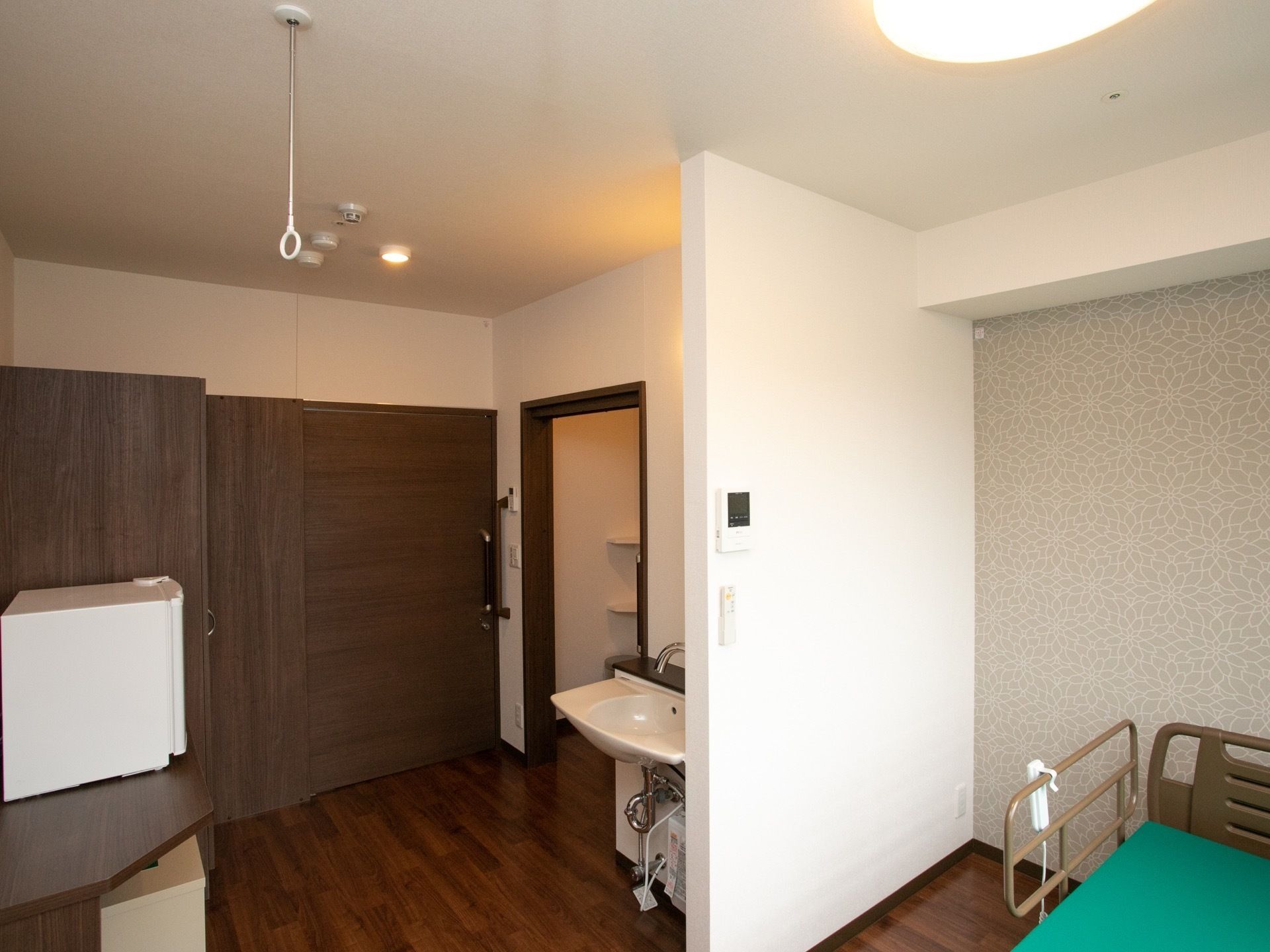 フローリングの居室に、ベッドが一台置かれている。部屋の入り口やトイレの扉は木製の引き戸になっている。