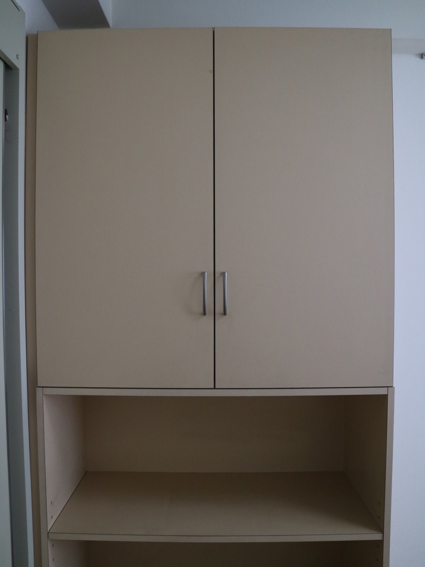 居室にあるグレーの落ち着いた色の戸棚である。上部が開き戸になっており、下の部分が二段の棚になっている。