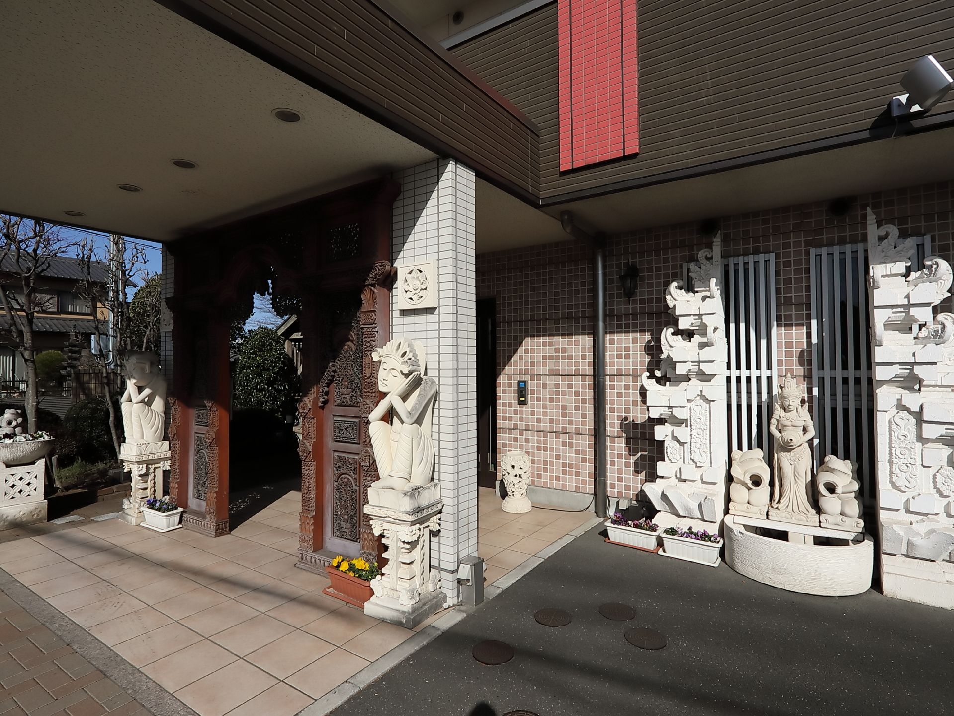玄関前には重厚な屋根が設置されているので、雨や風の日もご安心いただける。脇には手入れの行き届いた前栽が見られる。