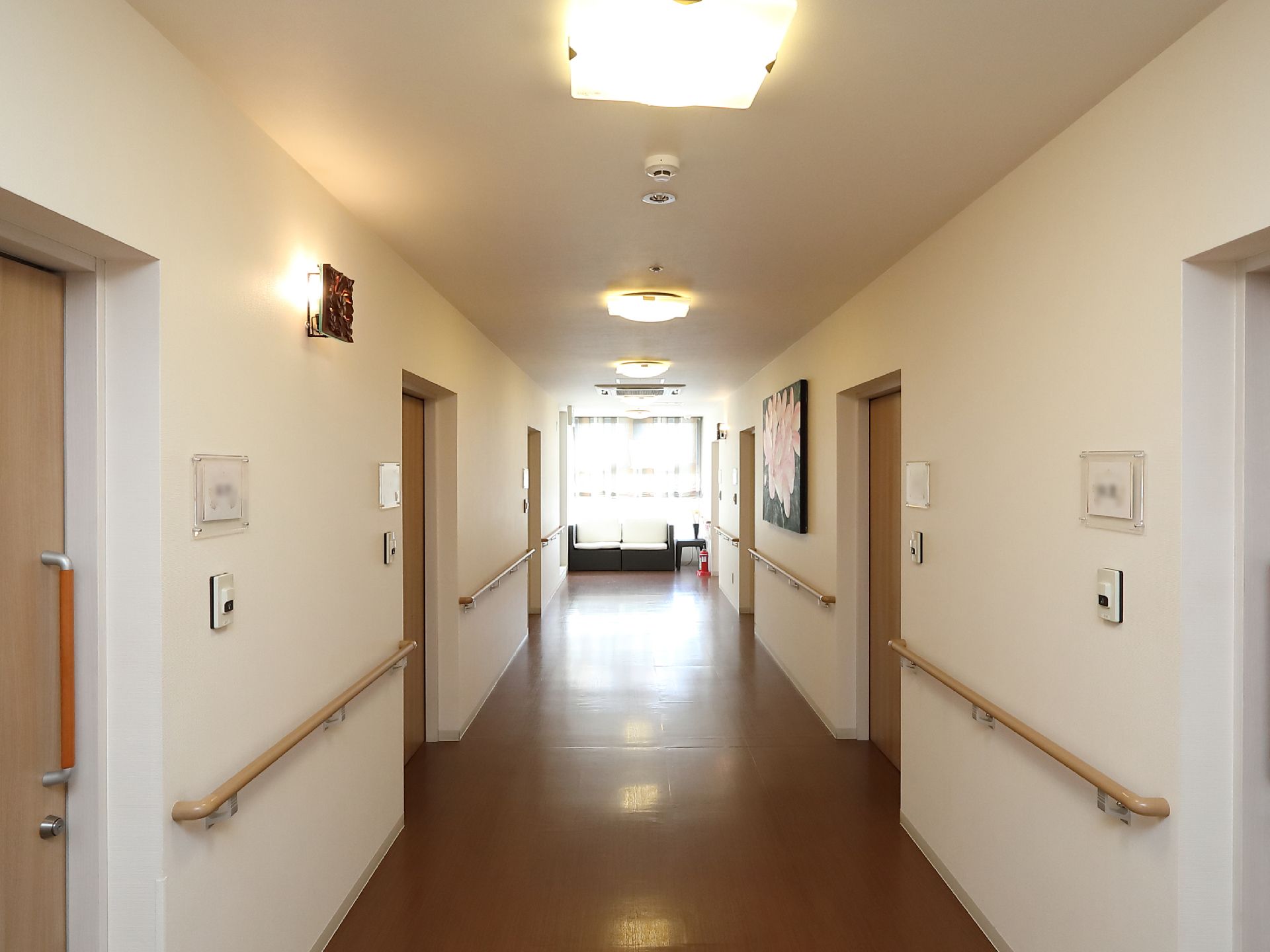 廊下には入居者様の円滑な歩行を促すための手すりが設置されている。一番奥のスペースには休憩用のソファが設けられている。