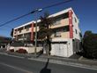 赤色の縦の模様が特徴的な、道路に面して建っている３階建ての施設である。敷地内に、大型の倉庫が置かれている。