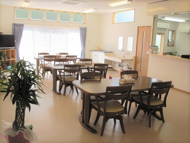 ダイニングテーブルが複数並んだ食堂に観葉植物やテレビもある。