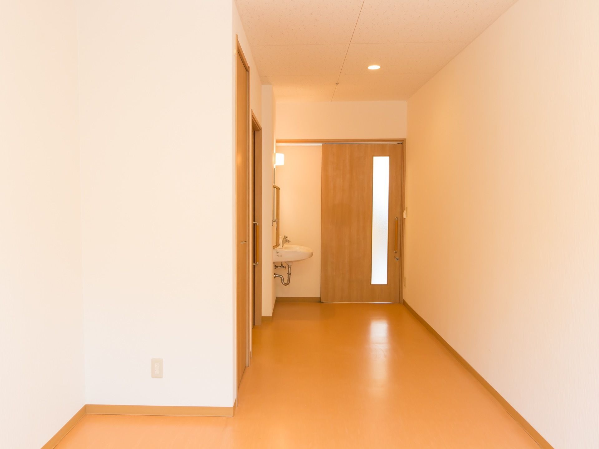 奥行きのあるフローリングの部屋がある。入口は引き戸になっていて、入ってすぐ脇に洗面台が設置されている。
