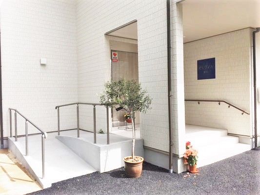 施設のエントランス部分に設けられたスロープの写真。奥のほうに階段部分も写っている