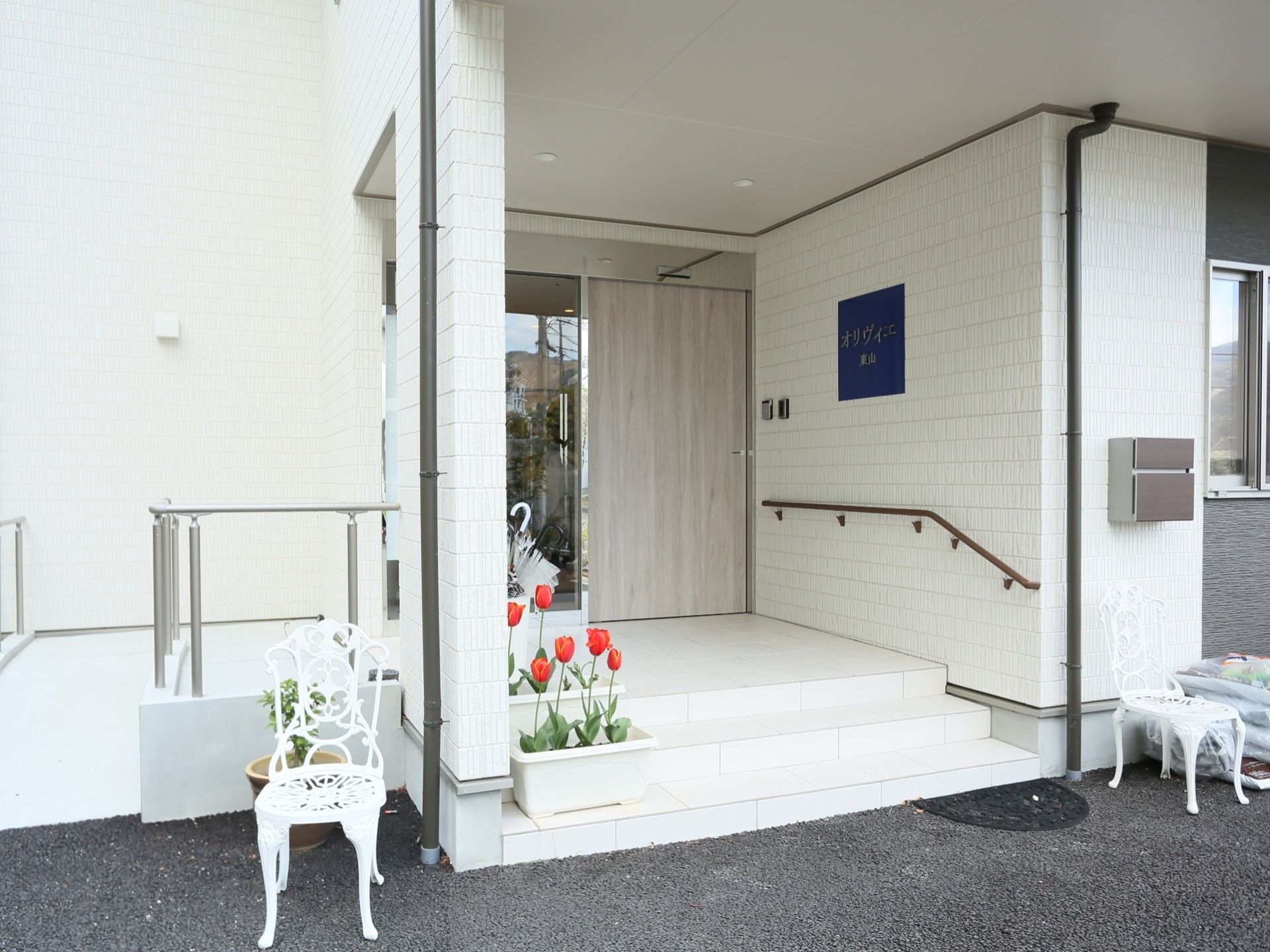 白を基調とした施設外観である。外壁には施設名が記された看板が設置されており、手すりが備えつけられている。