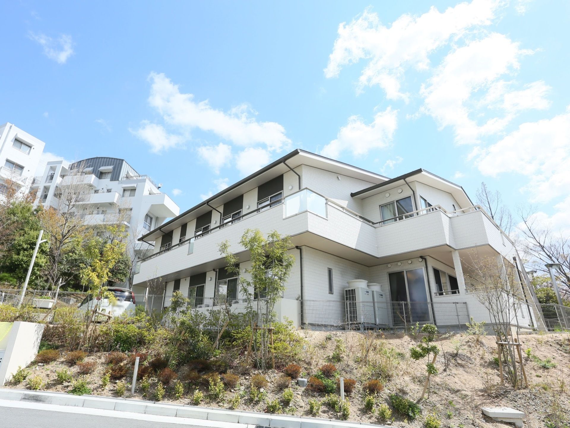 白を基調とした一軒家風の建物である。植栽が施されており、手入れが行き届いている。敷地内には車が停まっている。