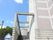 建物の横にはコンクリートの階段と手すりが設置されている。階段の手前にはプランターに植えられた植物が置かれている。