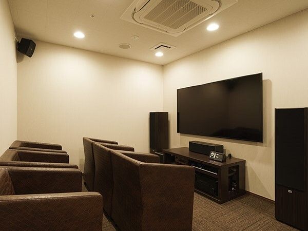 大きなテレビが設置された部屋には本格的な音響設備があり、黒い一人用の椅子が複数並んでいる。
