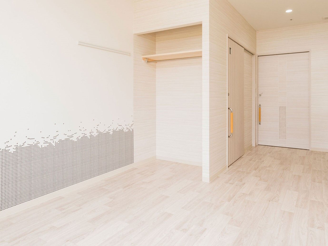 扉のないオープンタイプのクローゼットが設置されたフローリングの部屋。トイレのドアや居室のドアはスライド式。