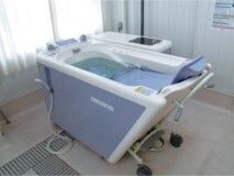 ブルーのチェアインバスが設置された浴室には窓も付いている。座ったまま入浴できる機械浴。