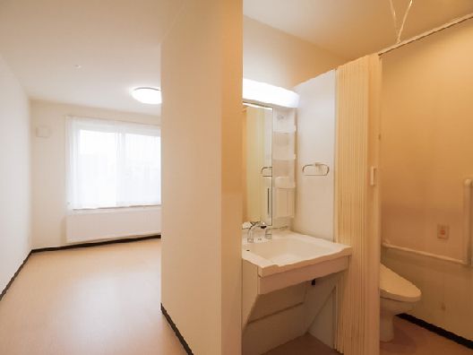 カーテンで開け閉めするタイプのトイレが付き車いす対応の洗面所もあり、大きな窓が付いている。