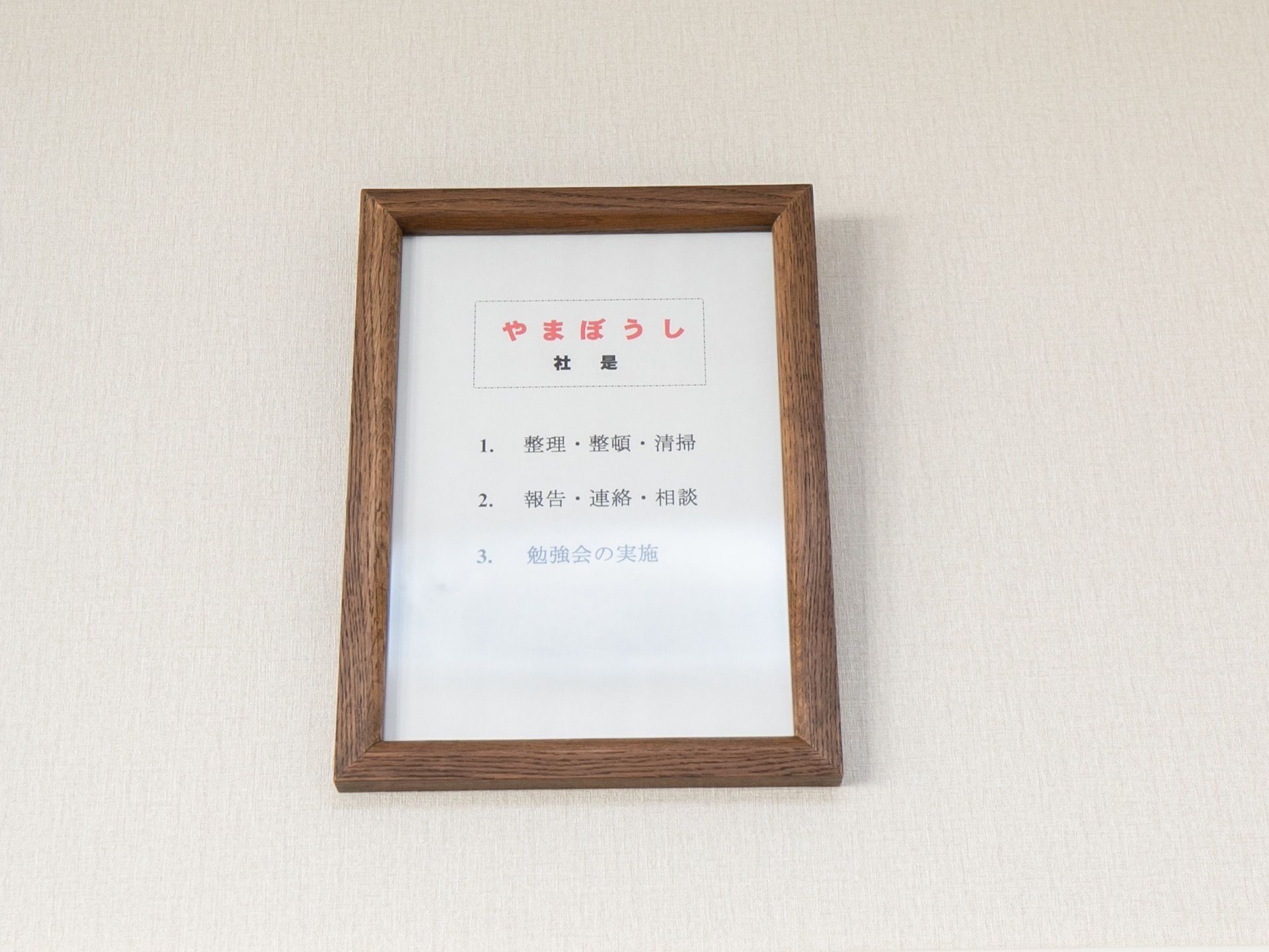 壁に社是が飾られている。施設では整理整頓や清掃、スタッフによる報連相を大切にしている。また、勉強会を積極的に実施していることが記されている。