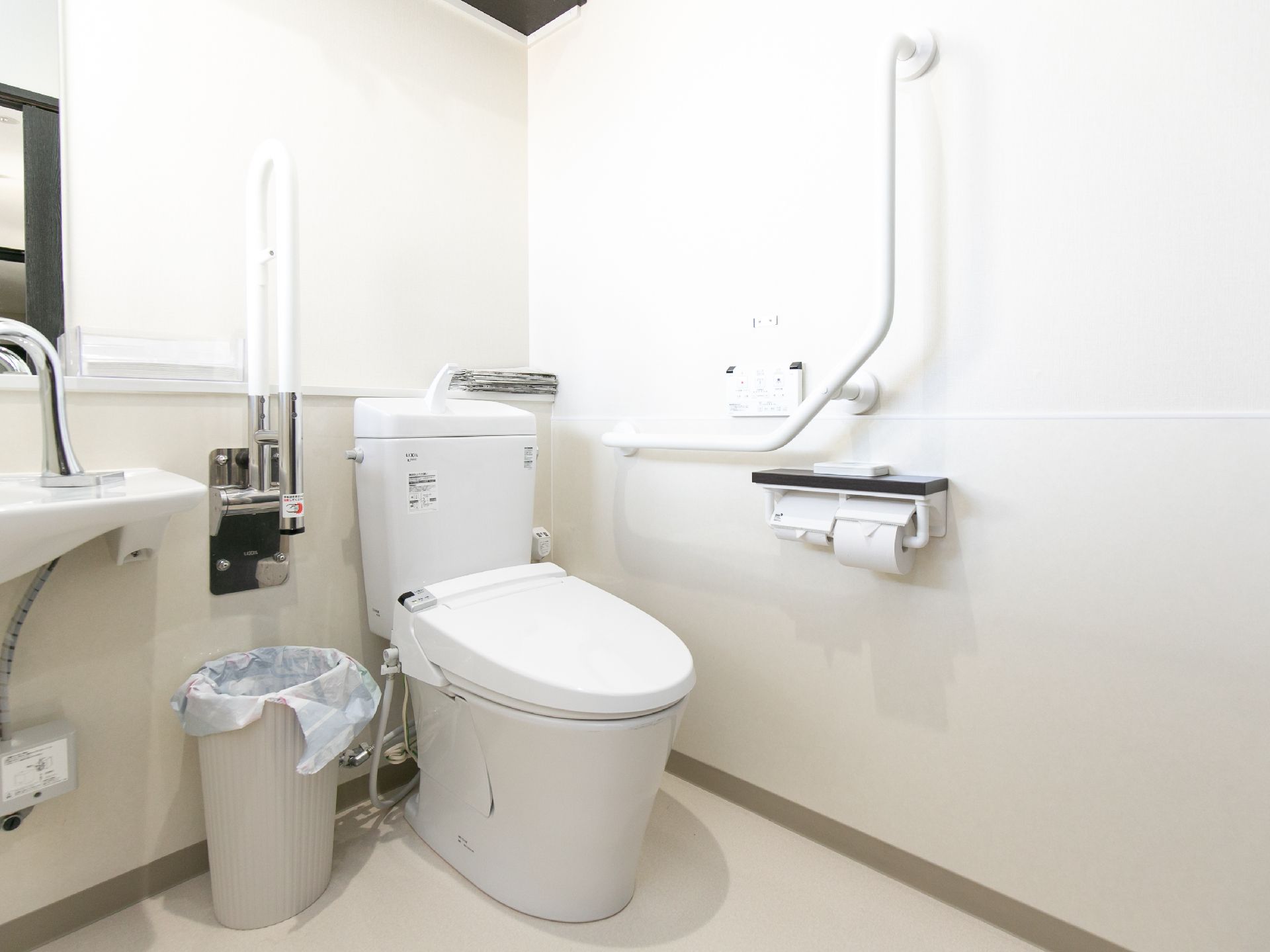 手すりが完備され、手洗い器も設置されているトイレの個室