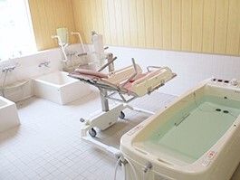 一人用の浴槽が２つ設置された広い浴室には寝台浴もある。お湯が溜められた浴槽のような機械の横にリフトがある。