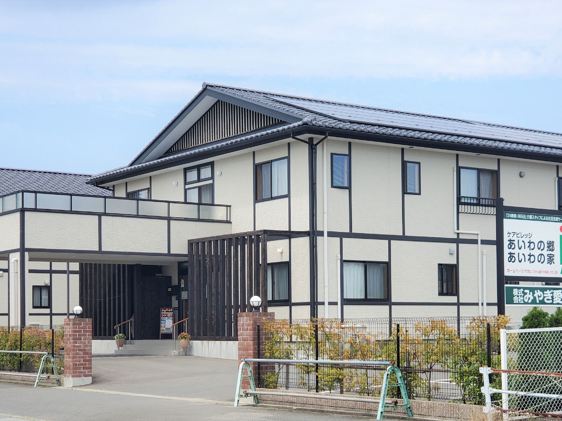 西洋風の一軒家のような建物の写真。車が入りやすい出入り口、雨除けとベランダが一体化された入り口が写っている