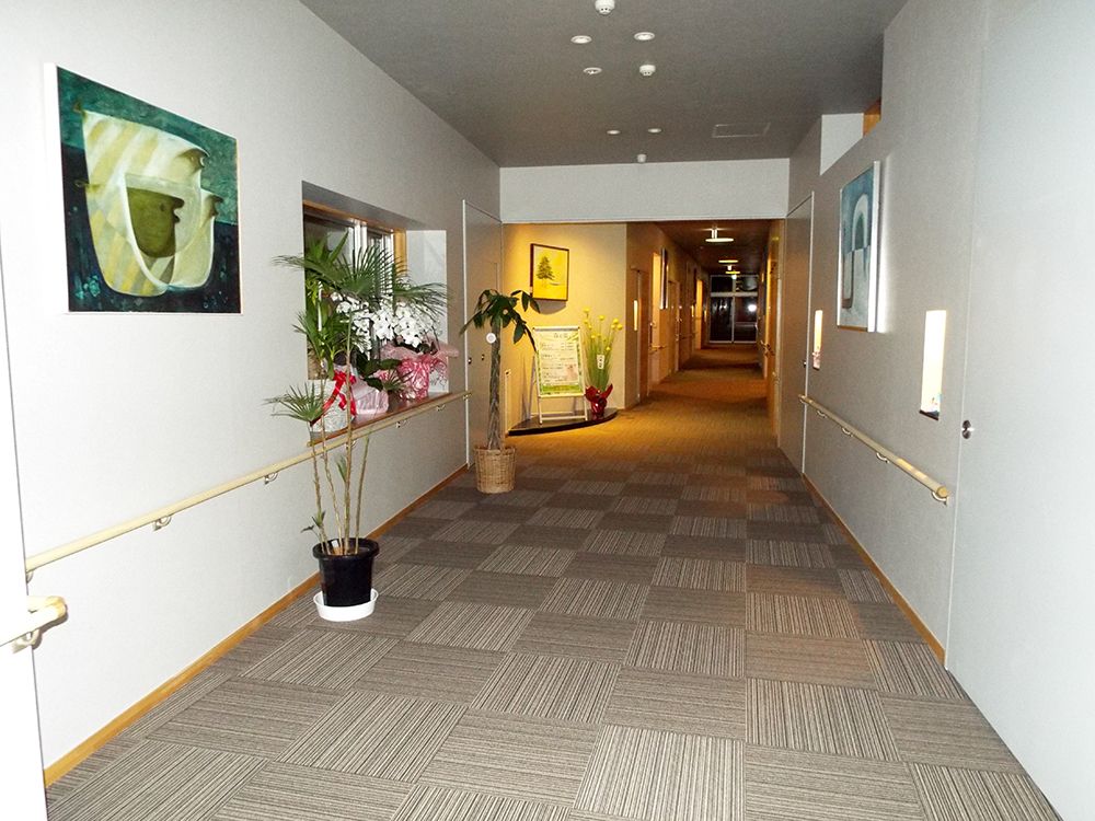左側の壁に絵画が掲げられている廊下の様子。どちらの壁にも手すりが取り付けられている