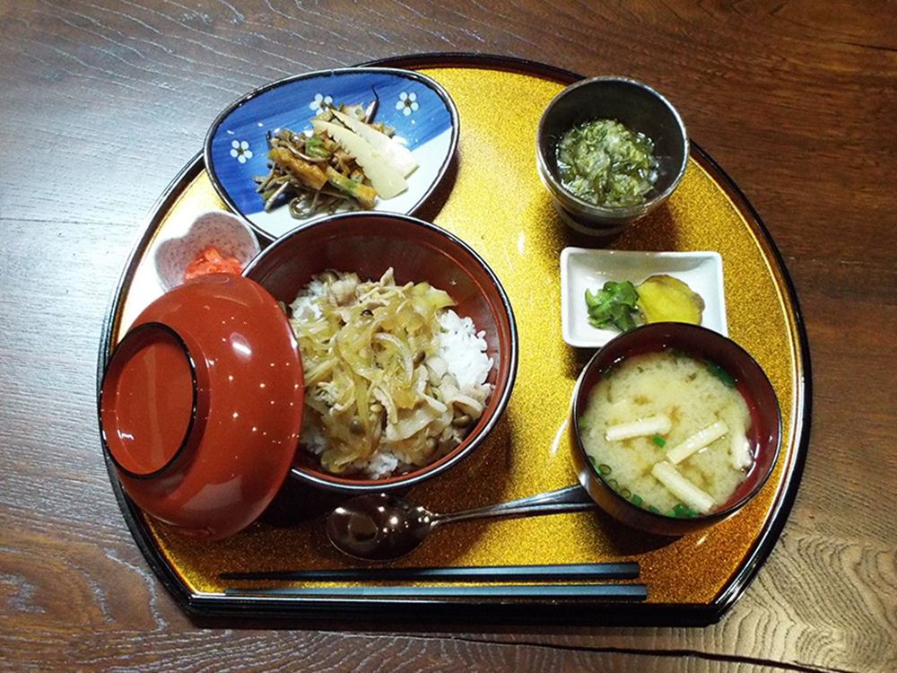 ごはんとみそ汁、その他のおかず類が半月型のお盆に乗ったメニューの写真