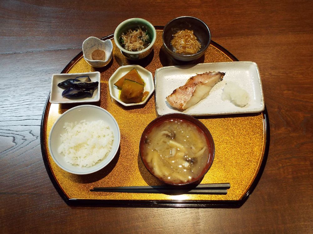 小さなおかず類と魚のおかず、ごはんとみそ汁がお盆に乗っている写真