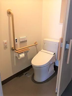 手すりと緊急コールがついた施設内のトイレの様子。車いすのまま入れる広さのトイレ