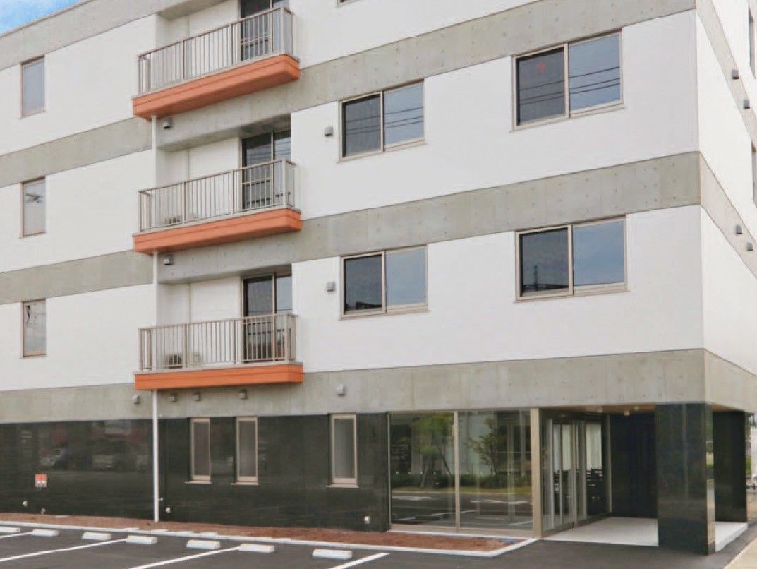 落ち着いたカラーリングの施設外観写真。オールバリアフリーのエントランス