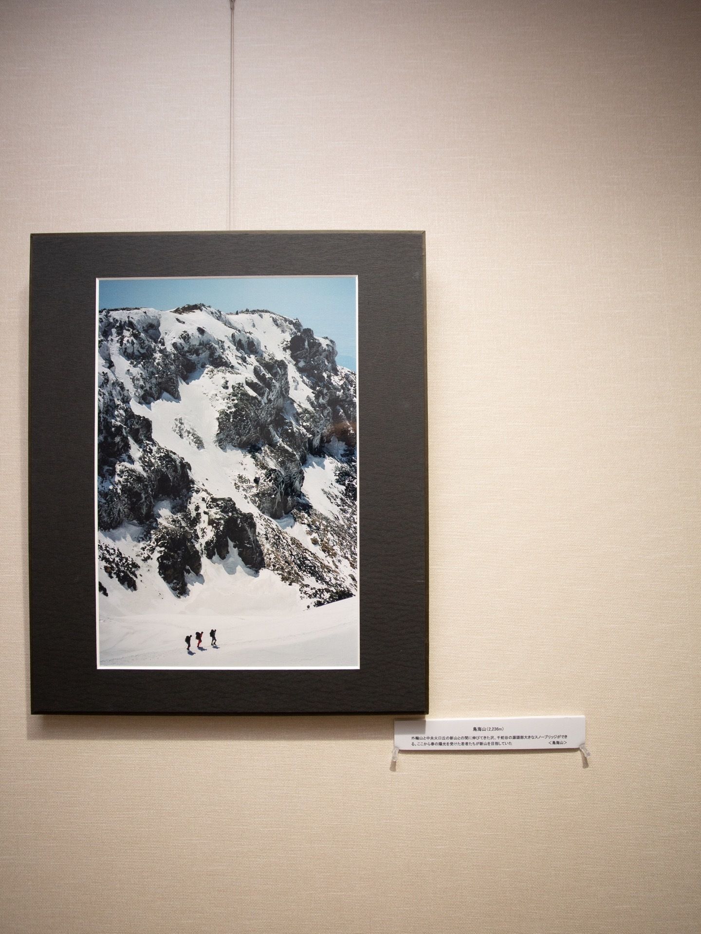 廊下の壁紙は白で統一されている。雪山の写真が飾られており、説明文が掲示されている。通路にはさまざまな写真がレイアウトされている。
