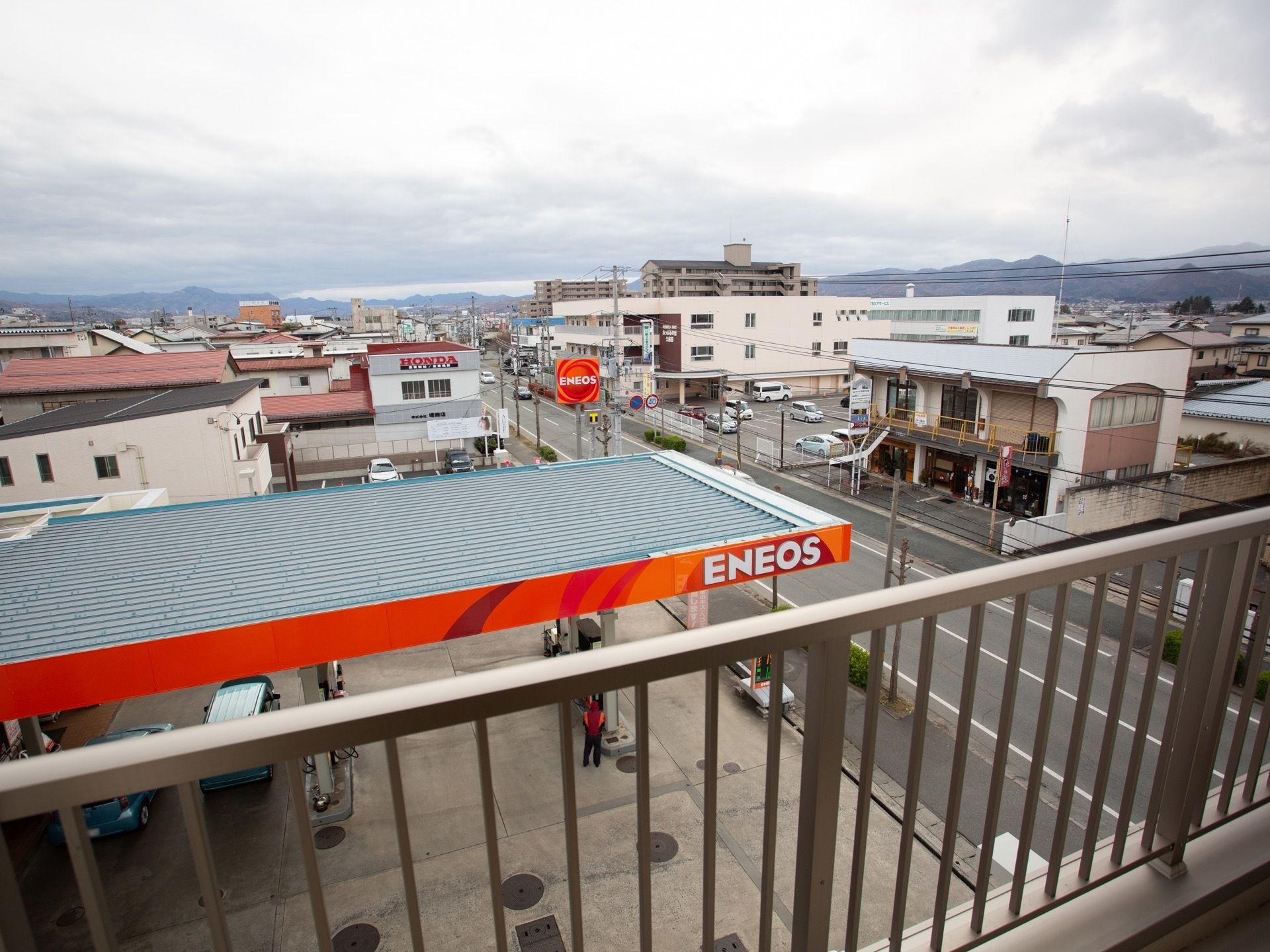 部屋のベランダからは、町内を眺めることができる。住宅街に位置しており、遠くには山を望むことができる。