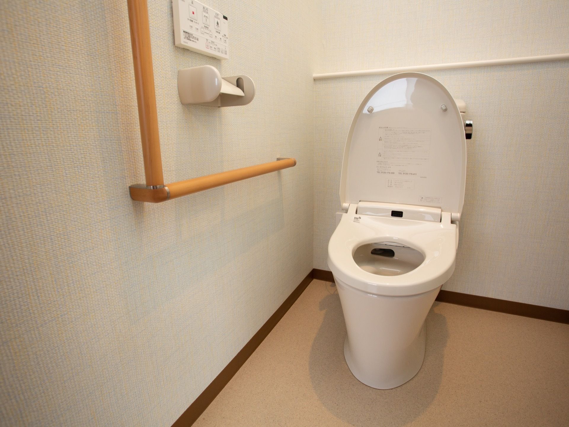 白を基調とした、温水洗浄便座つきのトイレが設置されている。壁には手すり、ペーパーホルダーが取り付けられている。